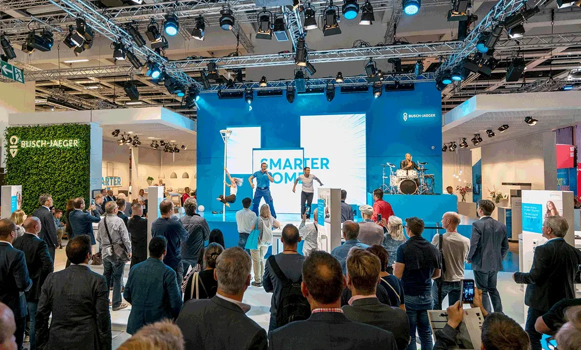Panel mit dem Titel „Smarter Home“ bei einer Veranstaltung, umgeben von Zuschauern und einem Musiker auf der Bühne.